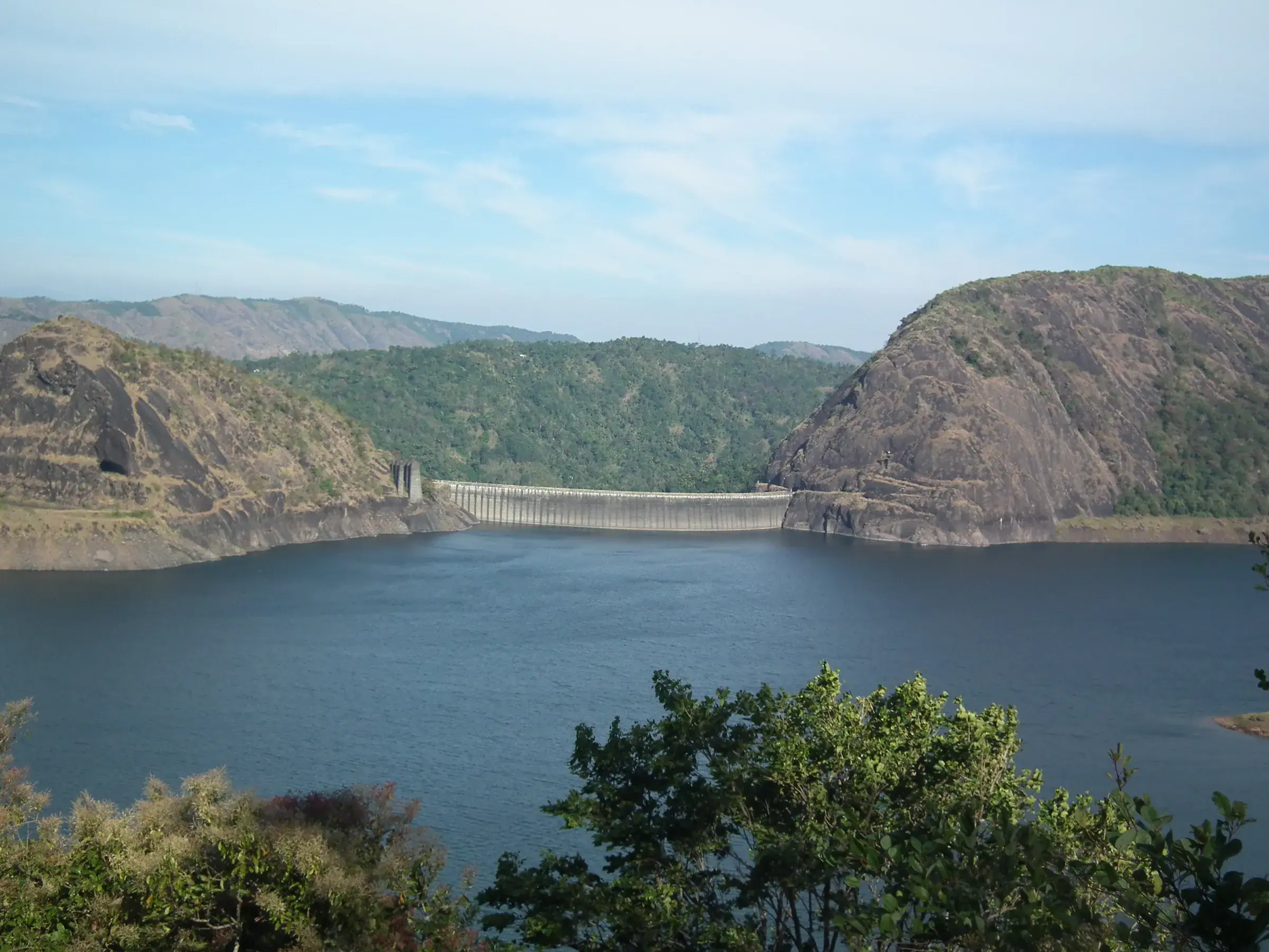The curved concrete wall of the Idukki Arch Dam between two hills
